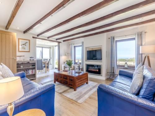 a living room with blue couches and a tv at Bay View Cottage in Llanon