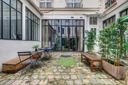 une cour avec des bancs et des tables dans un bâtiment dans l'établissement Stylish and sunny 7BD with garden for 17 guests!, à Paris