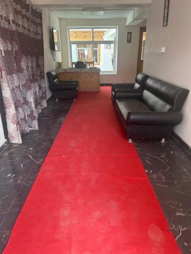 a red carpet in a waiting room with black leather furniture at Pacific Parlase in Leh