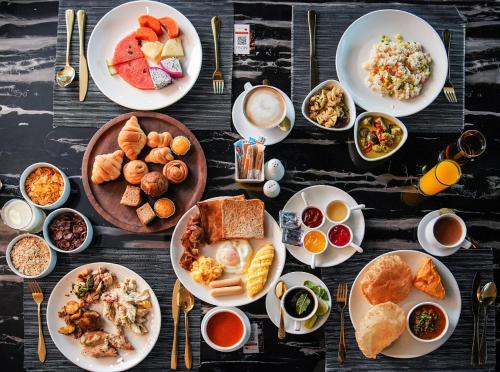 a table with plates of breakfast food on it at Ramada Sukhumvit Soi Eleven in Bangkok