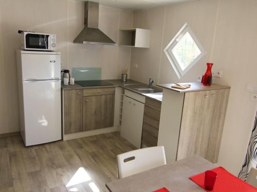 a small kitchen with a white refrigerator and a table at Domaine de Blangy in Hirson