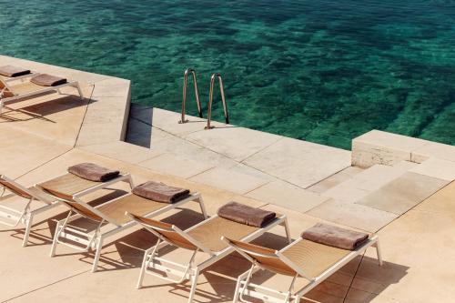 a group of chairs and tables next to the water at Hotel Bellevue in Mali Lošinj