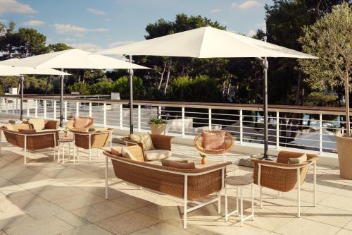 a group of chairs and umbrellas on a patio at Hotel Bellevue in Mali Lošinj