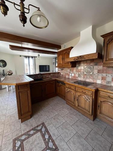 a large kitchen with wooden cabinets and a large island at Gîte du Camp de César - WIFI - 8 personnes in Bracquemont