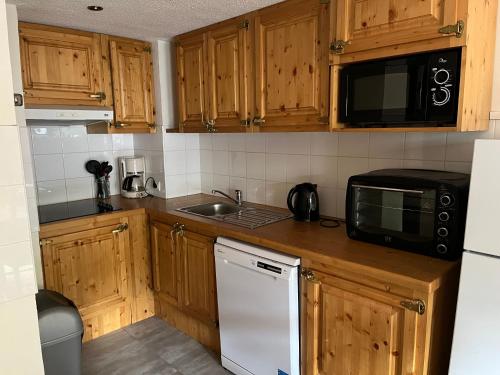 a kitchen with wooden cabinets and a white refrigerator at Chalet Alpina résidence Val Claret in Tignes