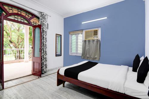 a bedroom with blue walls and a bed and a window at SmartStay by Brill Rooms in kolkata