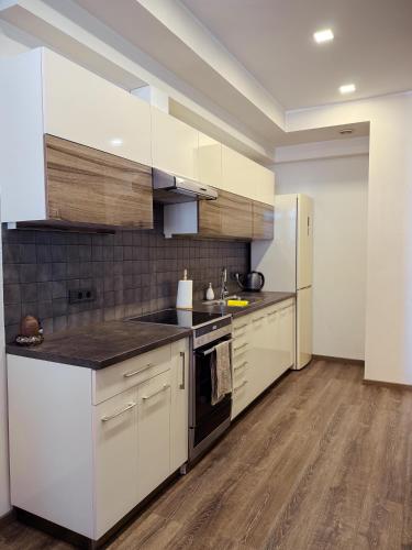Una cocina con gabinetes blancos y encimeras negras. en Cherry Tree House, en Ereván