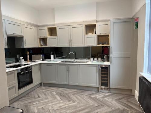 a kitchen with white cabinets and a wooden floor at Stylish 4 bed in Central Conwy in Conwy