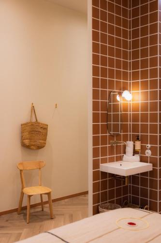 a bathroom with a sink and a chair at Hotel M Soleil - Montpellier Centre Saint Roch in Montpellier
