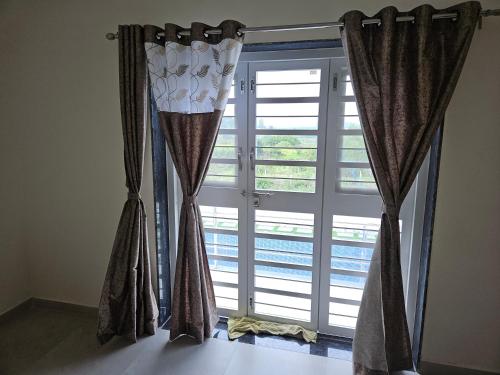 a window with curtains in front of a door at Rolling Hills in Nashik