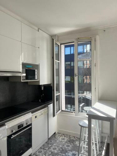 une cuisine avec des placards blancs et une grande fenêtre dans l'établissement Appartement Paris Expo Porte de Versailles, à Issy-les-Moulineaux