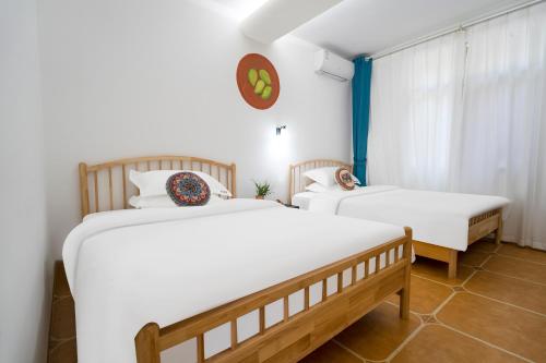 two twin beds in a room with a window at Mangshi Dianshan Xiyuan Homestay in Mangshi