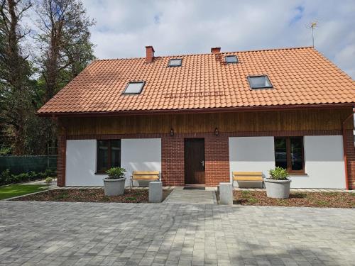 a brick house with two benches in front of it at Wczasowa 26 in Karwieńskie Błoto Drugie
