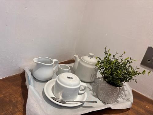 a table with two tea pots and cups on a table at Santalijshoteliers private entrance RM 1B in Leicester