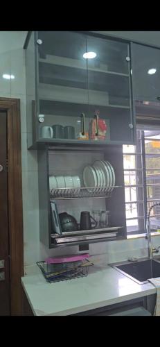 a kitchen counter with plates and dishes on shelves at Kim's Apartment in Agege