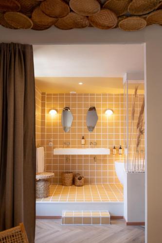 a bathroom with a yellow tiled wall at Hotel M Soleil - Montpellier Centre Saint Roch in Montpellier