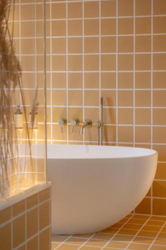 a white tub in a bathroom with orange tiles at Hotel M Soleil - Montpellier Centre Saint Roch in Montpellier