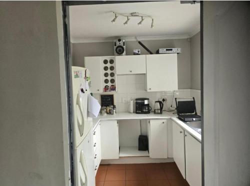 a small kitchen with white cabinets and appliances at The Chardonnay Inn in Centurion