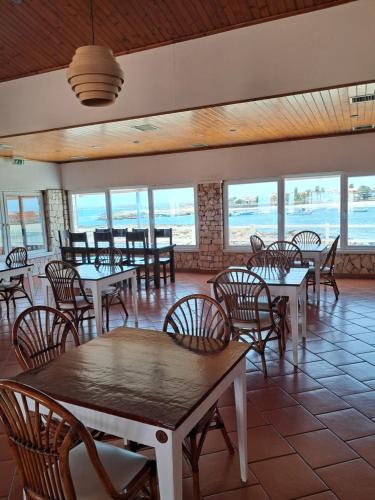a dining room with tables and chairs and windows at Vivenda Mia in Beirona