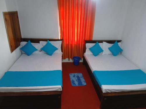 two beds in a room with a red curtain at Tea Leaf Family Cottage in Bandarawela