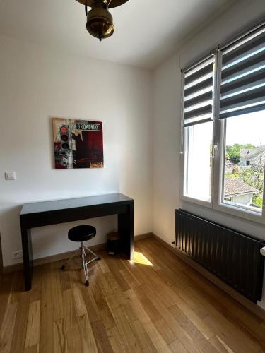 Una habitación con un escritorio negro y una ventana. en Esprit Londonien - WIFI - TV -, en Bracquemont