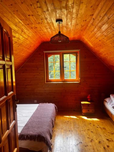 an attic room with a bed and a window at Stolove Chatki Radków in Wünschelburg