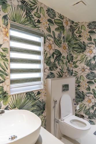 a bathroom with a toilet and a flowery wallpaper at Girisadan Boutique Stay in Jaipur