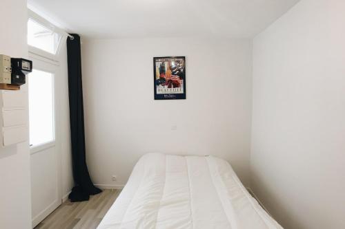 une chambre blanche avec un lit et un tableau sur le mur dans l'établissement Charming and cozy Near Montparnasse, à Paris