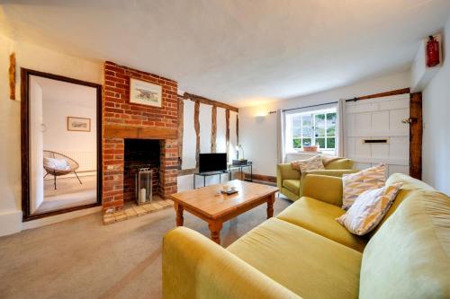 un salon avec un canapé et une cheminée dans l'établissement Countryside Cottage in Bulmer- Sleeps 6 7, à Sudbury