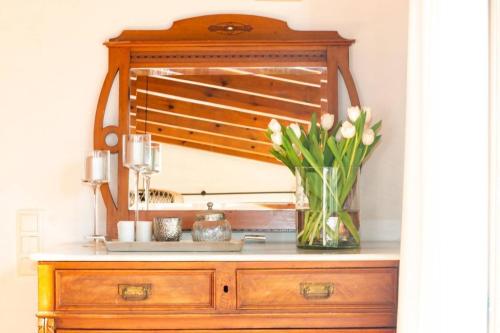 a vase of flowers on a dresser with a mirror at Finca Les Oliveres in Benissa