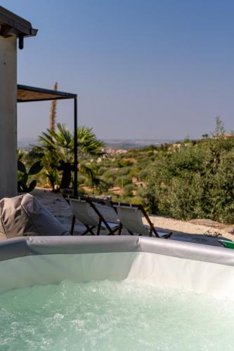 a swimming pool with two chairs and a table at Collemeti - Country House in Noto