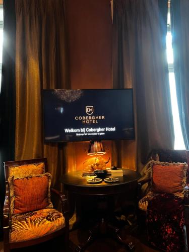 a room with a table and two chairs and a television at Cobergher Hotel in Kortrijk