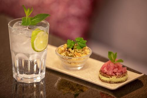 a glass of water and a plate with a sandwich and a drink at Rose Garden Palace Roma by OMNIA hotels in Rome