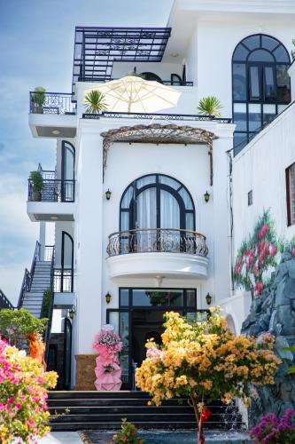 a white building with stairs and flowers in front at Eco Bliss Hotel in Thôn Lại Thê