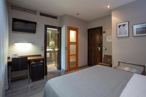 a bedroom with a bed and a desk with a computer at Hotel Gran Via in Zaragoza