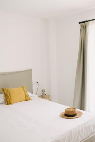 a hat sitting on top of a bed with a window at Curolla Petit Hotel in Maria de la Salut