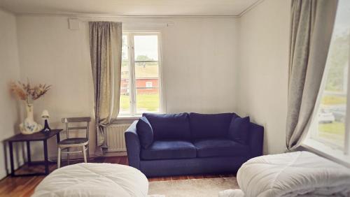 a living room with a blue couch and a window at Orrefors Vandrarhem in Nybro