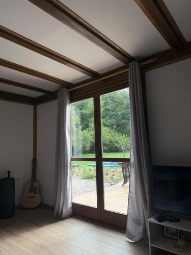 a room with a sliding glass door with a guitar at Vikendica Čardak in Srebrenik