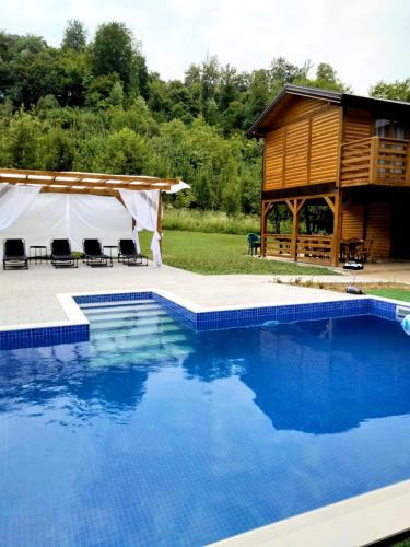 a large swimming pool in front of a cabin at Vikendica Čardak in Srebrenik