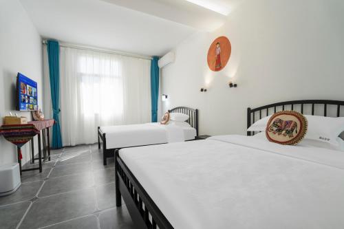 a hotel room with two beds and a window at Mangshi Dianshan Xiyuan Homestay in Mangshi