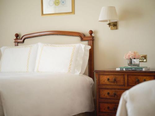 a bed with two pillows and a night stand with a lamp at The Savoy in London