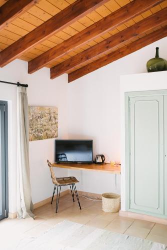 a room with a desk with a television and a chair at Curolla Petit Hotel in Maria de la Salut