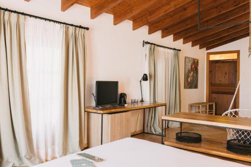 a bedroom with a bed and a desk with a television at Curolla Petit Hotel in Maria de la Salut