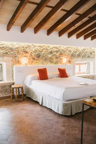 a bedroom with a large white bed with orange pillows at Curolla Petit Hotel in Maria de la Salut