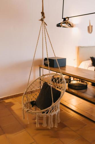 a hanging chair in a room with a table at Curolla Petit Hotel in Maria de la Salut