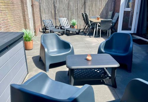 a patio with chairs and a table and a table and chairs at Ferienhaus Glücklich am Meer 3 mit Wellnesszugang in Egmond aan Zee