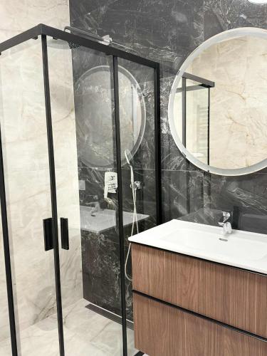 a bathroom with a shower and a sink and a mirror at Apartamenty Sokół in Drohiczyn
