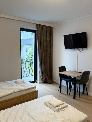 a hotel room with two beds and a table and a television at Apartamenty Sokół in Drohiczyn