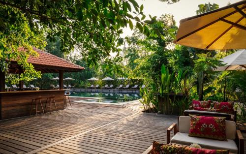 a wooden deck with chairs and a bar next to a pool at Farmhouse Resort & Spa in Kampong Chhnang
