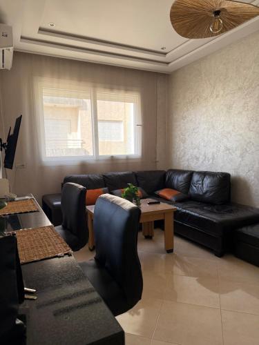 a living room with a black leather couch and a table at Cozy & Calm Apartment in Oulad Akkou